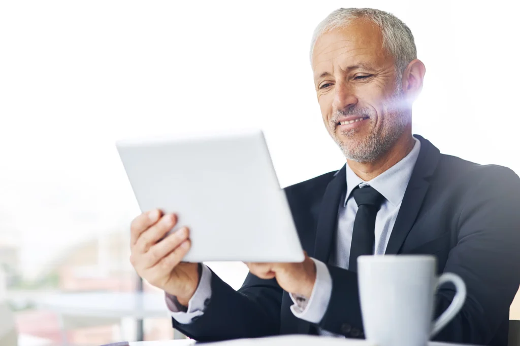 Empresario revisando información financiera en una tablet, representando el análisis del reporte de crédito para personas físicas y morales.