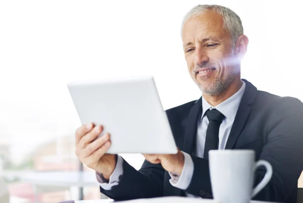 Empresario revisando información financiera en una tablet, representando el análisis del reporte de crédito para personas físicas y morales.