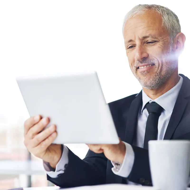 Empresario revisando información financiera en una tablet, representando el análisis del reporte de crédito para personas físicas y morales.