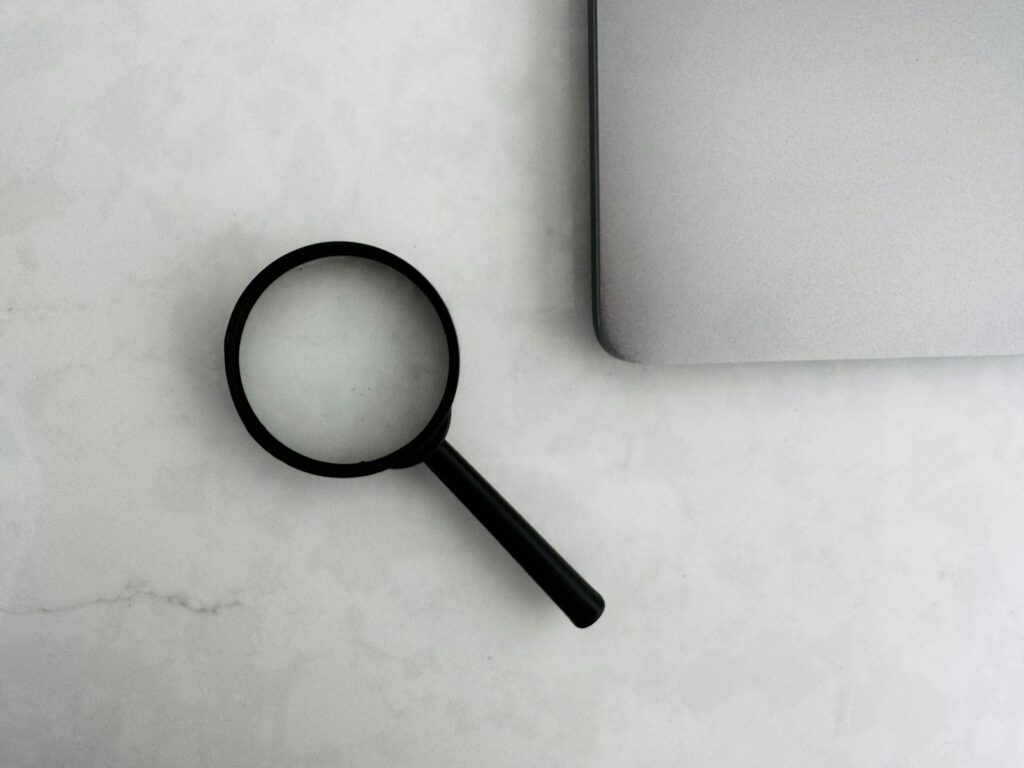 Lupa junto a una laptop para la investigación de clientes comerciales