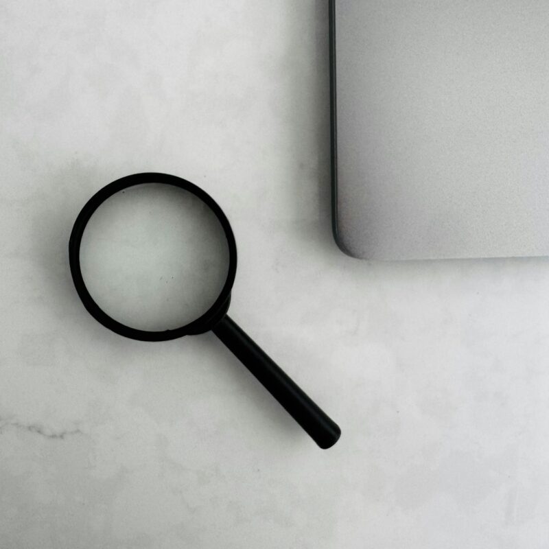 Lupa junto a una laptop para la investigación de clientes comerciales