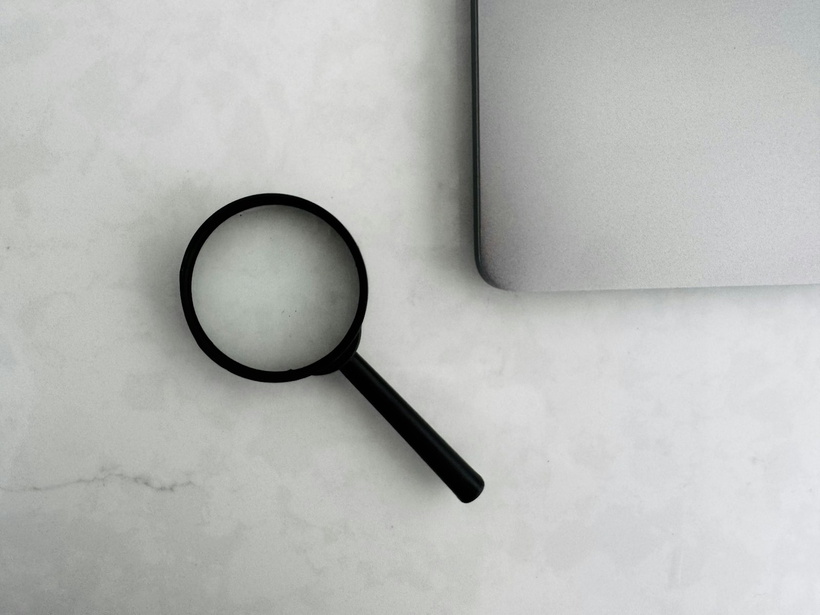 Lupa junto a una laptop para la investigación de clientes comerciales